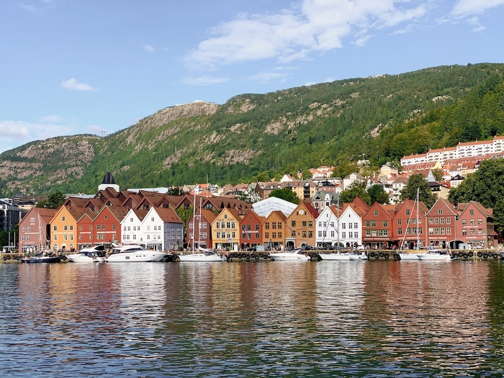 Waterfront with a row of colourful houses. Mountain in the background. Photo.